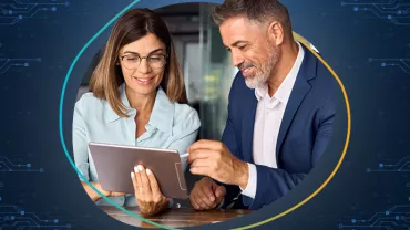 Due persone sorridenti guardano un tablet in un ambiente tecnologico.