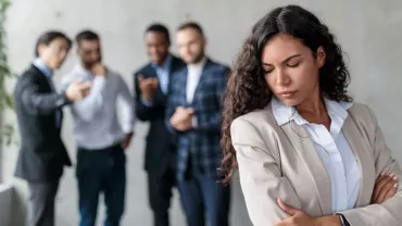 Episodio di mobbing sul lavoro con la donna in primo piano discriminata dai colleghi