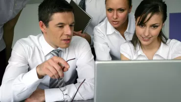 Gruppo di persone in ufficio che osservano uno schermo di laptop.