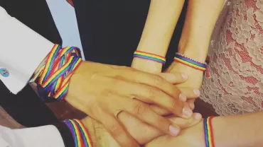 Mani unite con braccialetti arcobaleno.