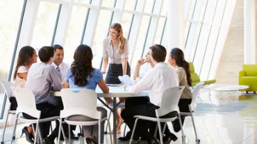 Persone in riunione intorno a un tavolo in ufficio moderno.