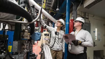 Due lavoratori in una fabbrica osservano un macchinario complesso.