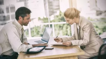 Due persone discutono in ufficio con un computer portatile.