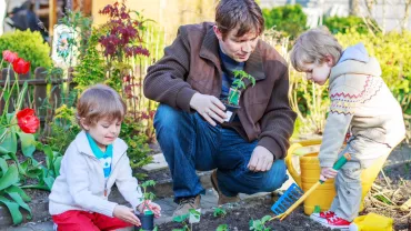 Famiglia che pianta fiori in giardino in una giornata di sole.